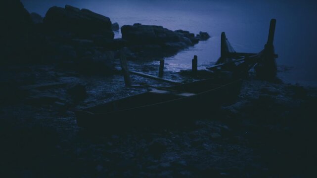 Moonlit wrecked boats on rocky shore, silhouetted against misty horizon, calm tide lapping pebbles, weathered hulls suggesting abandoned fishers memory, quiet
