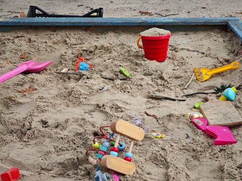 Colorful kids toys scattered in wooden sandbox on playground horizontal