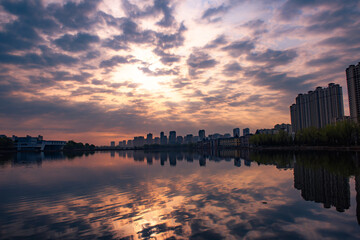 Fototapeta premium Urban lakeside park dusk scenery, buildings reflection on lake water