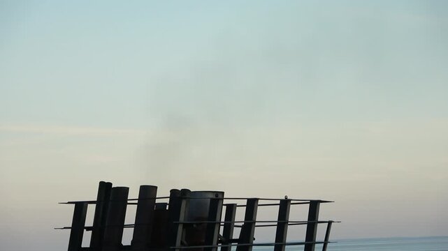 Ship funnel silhouette releasing smoke into the air