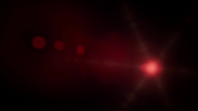 A glowing red lens flare effect with bright starburst light against dark background
