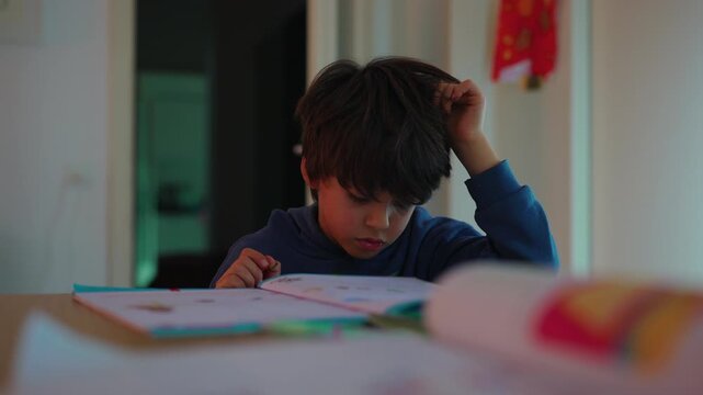 Young learner reading and thinking over an educational workbook at home desk, solving activities with curiosity, persistence, problem-solving and self-directed growth