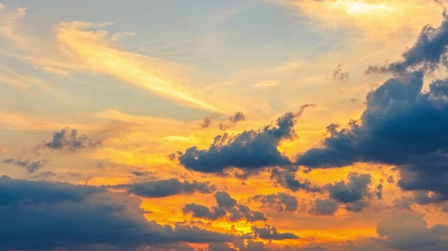 Dramatic sunset sky with golden light and dark cumulus clouds.