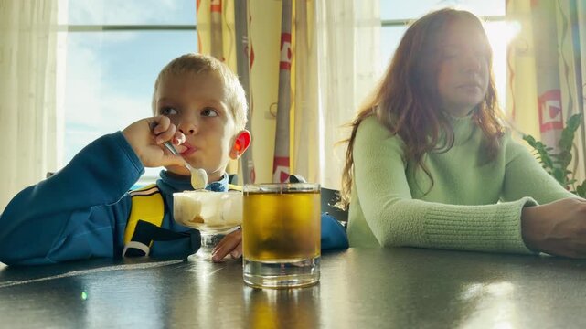 A mother and son eat dessert inside a cruise ship on Lake Ladoga. This cozy moment evokes a happy, joyful, and peaceful feeling.