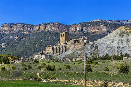 Church of Our Lady of the Assumption in Asso Veral, Spain, distant view. Romanesque temple with scenic mountain rocks behind