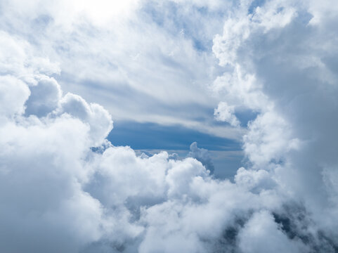 Aerial view of fluffy white clouds drifting across a clear blue sky over France.