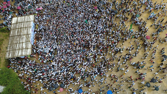 Cox's Bazar, Chittagong Division, Bangladesh - 25 August 2026: Aerial view of a large crowd gathered at a Rohingya refugee camp with people standing near a makeshift stage.