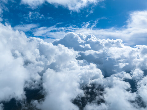 Aerial view of dense white cumulus clouds floating in a bright blue sky over France.