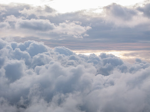 Aerial view of a dense layer of fluffy white clouds illuminated by soft sunlight in the atmosphere above France.