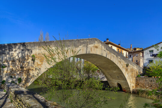 Picudo Bridge in Estella, Spain, scenic side view. Medieval gothic stone arch bridge over Ega river with water reflection
