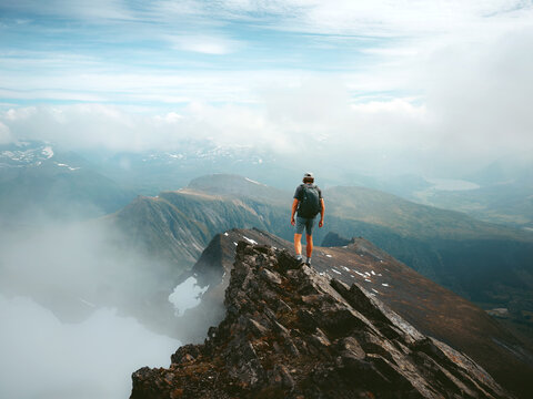 Man climbing solo in Norway reaching mountain summit in Sunnmore Alps on travel adventure extreme vacations, active mountaineer enjoying outdoor exploration freedom endurance healthy lifestyle