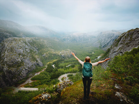 Traveler woman explore Norway hiking solo in Rago park mountains travel healthy lifestyle freedom female tourist raised hands on active adventure vacations trip outdoor enjoying foggy nature view