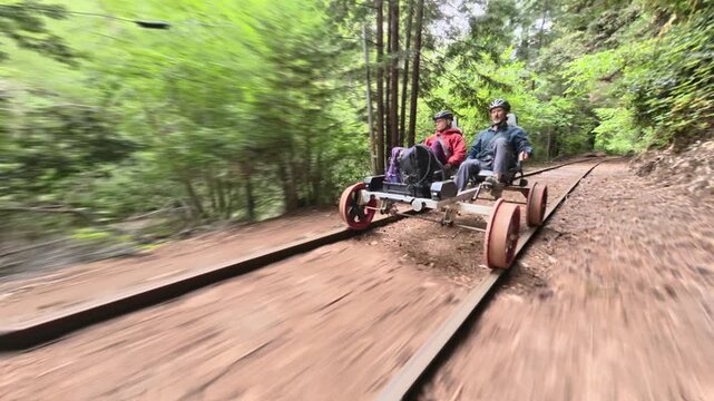 Couple rides an electric railbike over old railroad tracks through redwood trees and across bridges in Fort Bragg California.