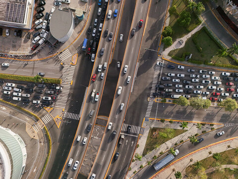 Aerial view of Avenida Abraham Lincoln with heavy traffic flowing through a busy urban intersection surrounded by green spaces in Santo Domingo, Distrito Nacional, Dominican Republic.
