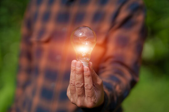 Farmer Holding Glowing Light Bulb for Green Energy and Sustainable Agricultural Innovation Concept