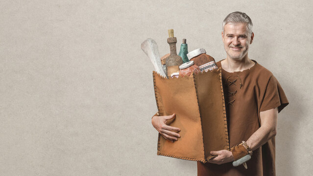 Smiling Caveman Carrying Leather Shopping Bag with Primitive Stone Groceries