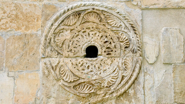 Ornate circular stone carving medallion depicting classical leaf motifs and elaborate geometric designs, showcasing centuries old craftsmanship on a weathered building facade