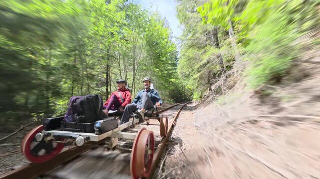 Mature couple enjoys an electric railbike adventure on old railroad tracks in Fort Bragg California near redwood trees and bridges.