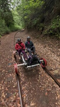Couple enjoys electric rail bike ride over old railroad tracks in redwood forest near Mendocino California with beautiful scenery.