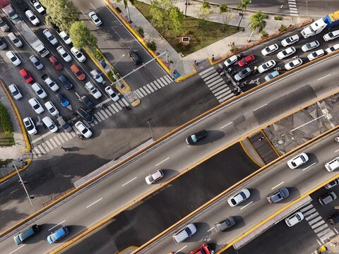 Aerial view of heavy traffic on the Avenida John F. Kennedy highway intersection with cars and trucks moving through the urban landscape of Santo Domingo, Distrito Nacional, Dominican Republic.