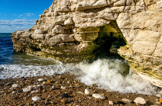 Breaking waves surge into a chalk sea cave at Flamborough Head on the Yorkshire coast, England, showing the power of coastal erosion.