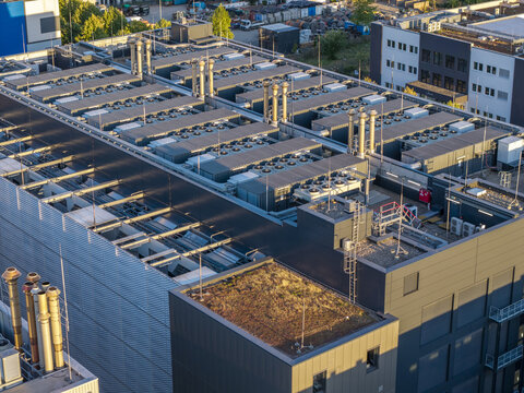 Aerial view of a modern data center rooftop featuring numerous industrial HVAC cooling units, ventilation pipes, and a section of green roof in Frankfurt am Main, Hessen, Germany.