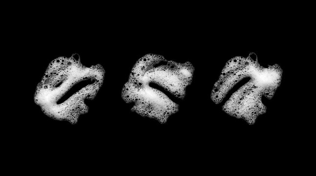 White foam bubbles forming three abstract organic shapes on a black background, creating a monochrome texture for beauty, cleaning, skincare, bath, product advertising, and creative design.