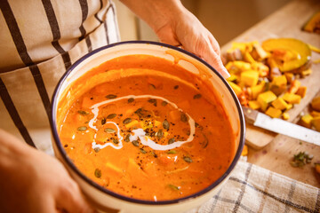 Creamy pumpkin soup garnished with seeds and herbs