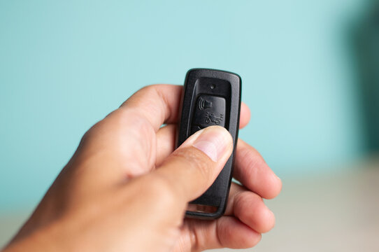 Close up of hand pressing motorcycle key fob remote button to unlock a vehicle