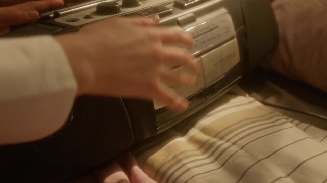 Cropped shot of unrecognizable girl inserting cassette tape into vintage boombox player and closing deck, close up. Ideal for nostalgic marketing campaigns and retro music technology promotions