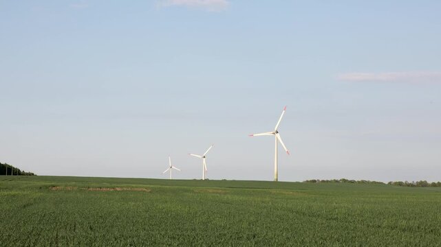 Wind turbines rotating over green agricultural field on a sunny day