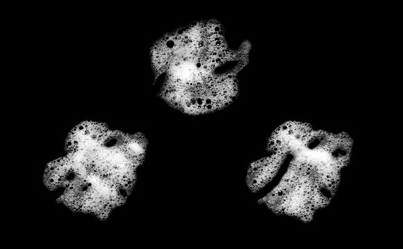White soap foam bubbles isolated on black background with realistic cleaning texture, abstract liquid pattern and detailed detergent lather for hygiene, skincare and cleaning design concepts.