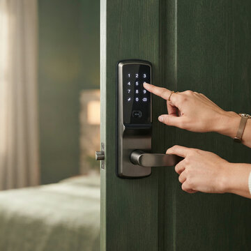 Woman pressing a digital lock keypad on a dark green wooden door under gentle light