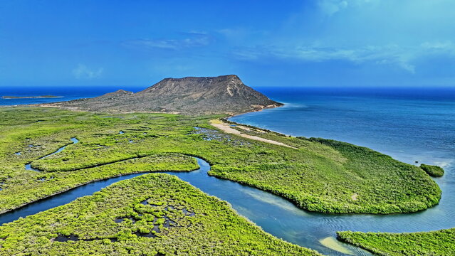 Aerial view of the iconic El Morro mountain rising above the lush green mangrove forests and the turquoise waters of the coastline in Monte Cristi, Monte Cristi Province, Dominican Republic.
