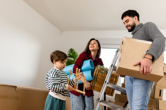 Family carrying moving boxes and household items together at home