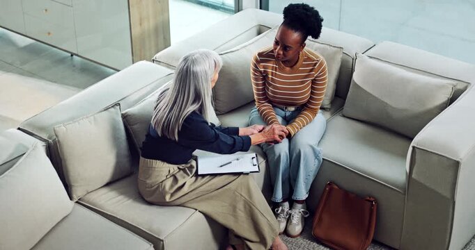 Sad, woman and psychologist holding hands for counseling, emotional support or empathy. Above, therapist and patient with depression for care, trauma recovery or coping assistance with clipboard