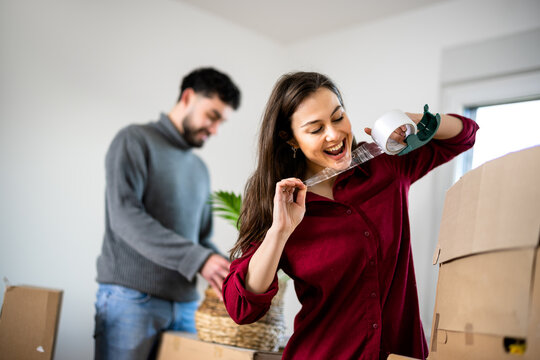 Woman drinking from a bottle beside cardboard boxes while moving home