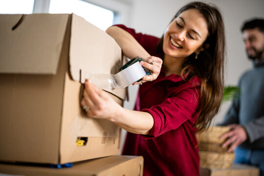 Woman packing a cardboard box with tape during a home move