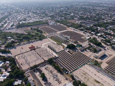 Aerial view of CFE Merida Area electric substation and solar panel arrays, surrounded by urban residential areas and green vegetation in Merida, Yucatan, Mexico.