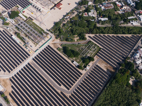 Aerial view of the CFE Merida Area solar farm featuring rows of photovoltaic panels, an electrical substation, and surrounding vegetation in Merida, Yucatan, Mexico.