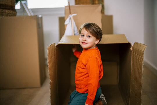 Young boy standing among cardboard boxes during a home move