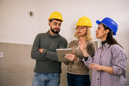Construction team discussing renovation plans with a tablet indoors