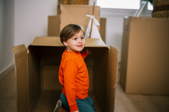 Young boy standing beside cardboard boxes during a family move
