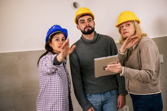 Construction team discussing renovation plans in an unfinished room