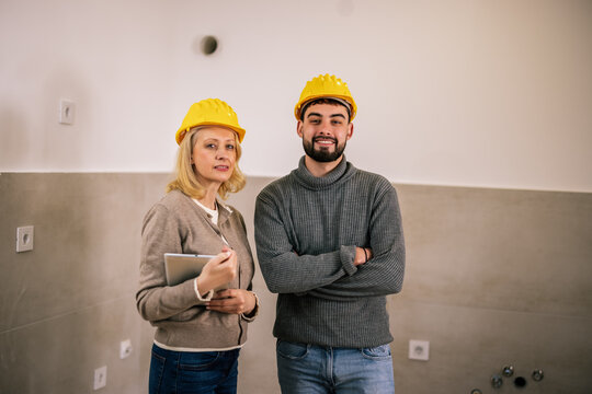 Construction worker and colleague standing together in an unfinished room