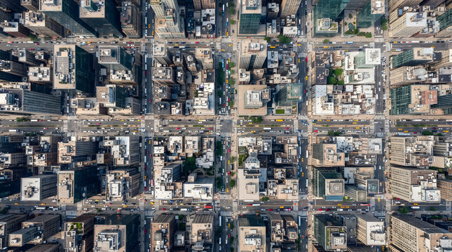 Aerial view of cars driving on city streets in a dense urban grid layout.
