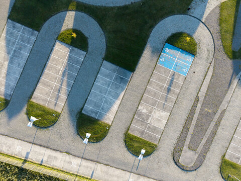 Aerial view of a modern parking lot with U-shaped parking bays, green grass patches, and a blue designated handicapped parking space in Krakow, Lesser Poland Voivode, Poland.