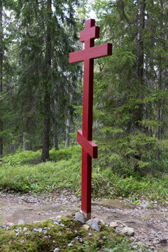 View of a red Orthodox cross standing in a lush forest on the Solovetsky Islands, Solovetsky, Arkhangelsk Oblast, Russia.