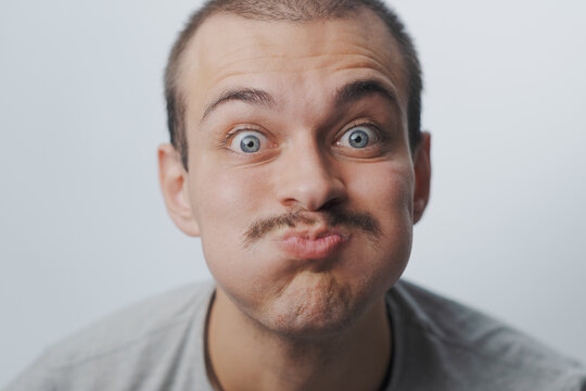 Funny young man with mustache puffing out his cheeks and making a silly face
