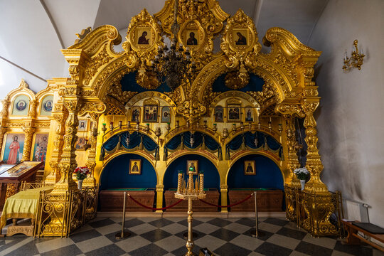 View of the ornate golden iconostasis with intricate carvings, religious icons, and blue drapery inside the historic Solovetsky Monastery in Solovetsky, Arkhangelsk Oblast, Russia.